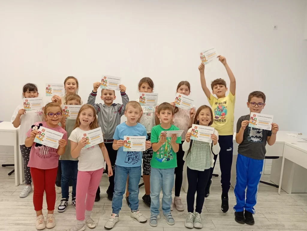 Poza de grup cu copii si lucrarile lor din impul cusrurilor de la scoala de vara
